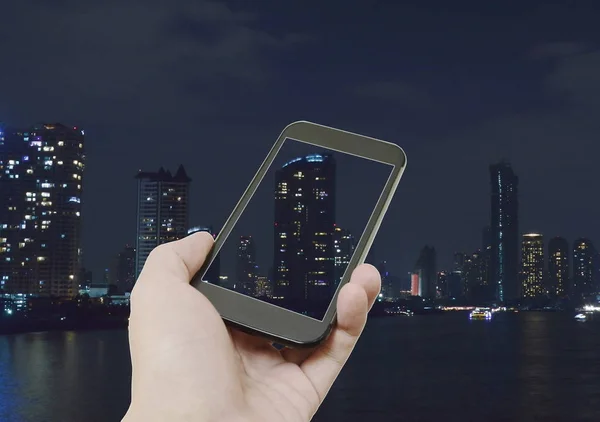 mobile phone holding on human hand with night city background