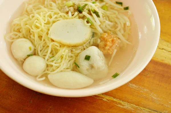 Macarrão chinês ovo topo bolinho de peixe e bola de camarão em sopa clara na tigela — Fotografia de Stock