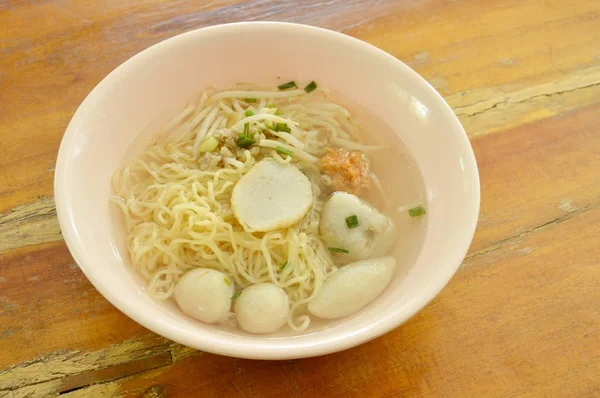 Mie telur Cina topping pangsit ikan dan bola udang dalam sup yang jelas di mangkuk — Stok Foto