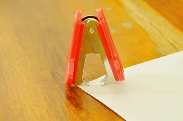 Heftklammerentferner zieht Draht aus Papier auf Holztisch — Stockfoto