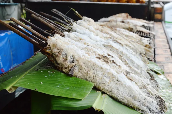 snake head fish wrapped with salt and grilled on fresh banana leaf in market