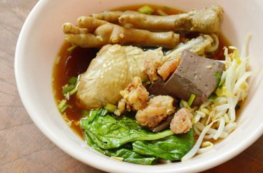  Haşlanmış tavuk budu ve ayakla fasulye filizi kahverengi bir çorba kasesinde.