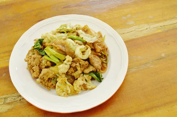 Tagliatelle di riso fritto con carne di maiale e verdure in salsa di soia nera sul piatto — Foto Stock