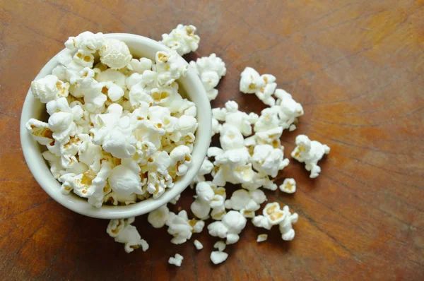 Salziges Popcorn im Becher auf Holztisch — Stockfoto