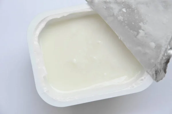 Yaourt ouvert à partir d'une tasse en plastique sur fond blanc — Photo