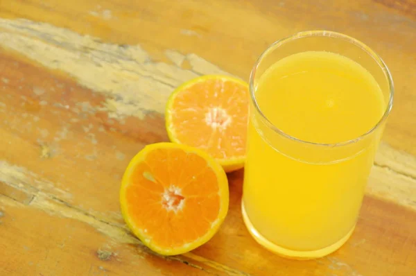 Jus d'orange en verre et mandarine sur planche de bois — Photo