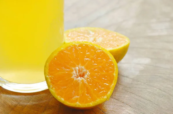 Jus d'orange en verre et mandarine sur planche de bois — Photo