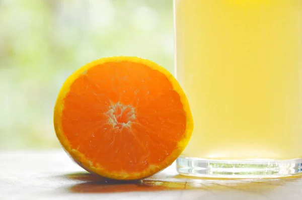 Апельсиновий сік у склі та мандарині, що ріже на дерев'яній дошці — стокове фото
