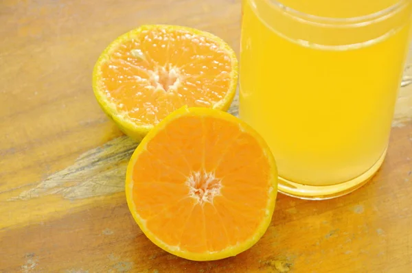 Jus d'orange en verre et mandarine sur planche de bois — Photo