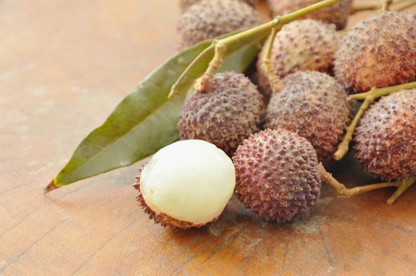 Lychee frutas tropicais descascar no fundo de madeira — Fotografia de Stock