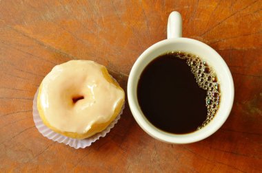  Beyaz kremalı donut ve ahşap tahta arka plan üzerinde siyah kahve fincanı