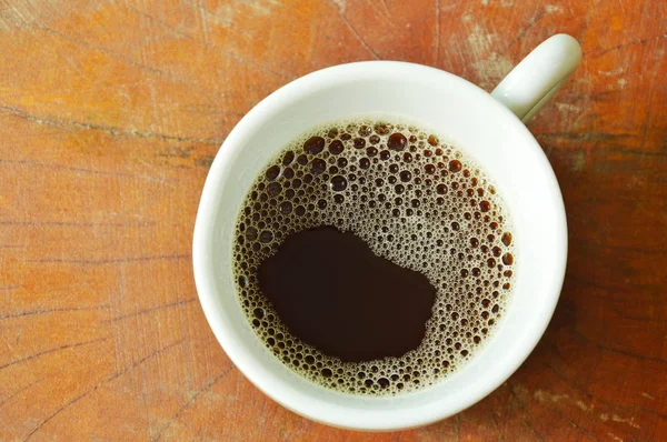 Czarny gorącej kawy w filiżance na drewnianym stole — Zdjęcie stockowe