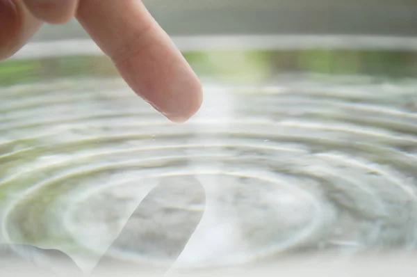 human finger touching on water surface