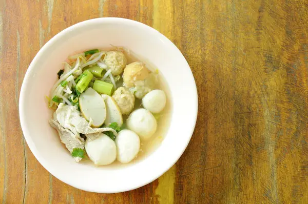 Pescado hervido y bola de camarones rematando carne de cerdo en sopa clara en un tazón — Foto de Stock