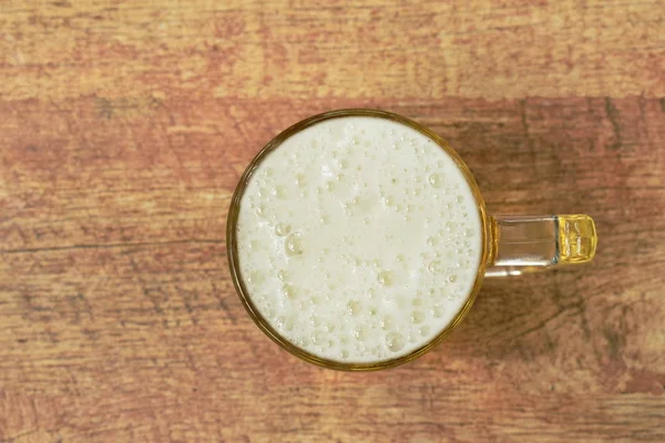 Kaltes Bier mit schäumendem Schweben im Glas auf dem Tisch — Stockfoto