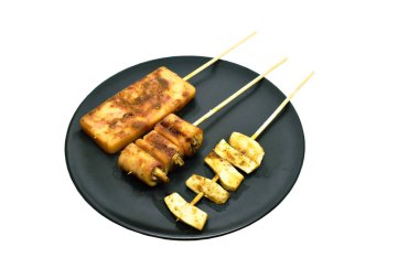 Izgara domuz pastırması doldurulmuş mantar mantarı ve domuz sucuğu dilimlenmiş shiitake mantarı soslu Sichuan biberi sosu ahşap çubuğa saplanmış.