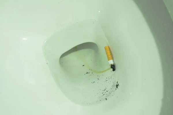 Сигаретний фільтр, що плаває в каналізаційному отворі туалету — стокове фото