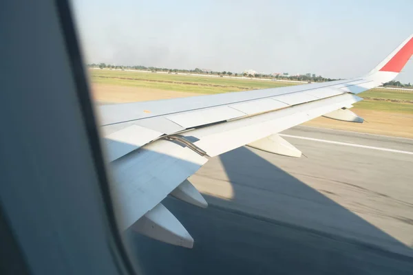 Ala de avión mientras despega de la pista del aeropuerto a través del marco de la ventana — Foto de Stock