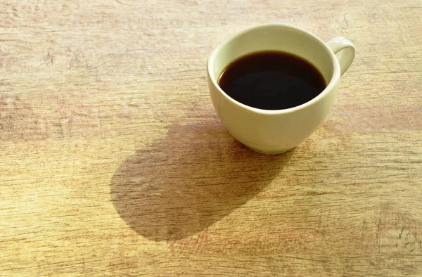 Чорна гаряча чашка кави на столі з ранковим сонячним світлом — стокове фото