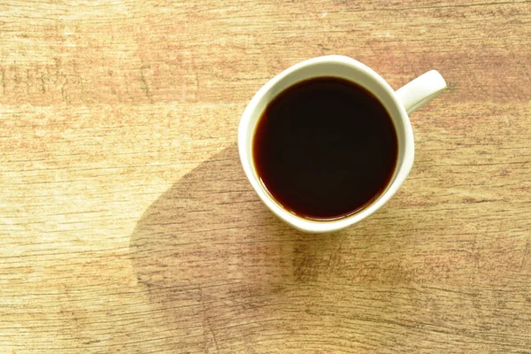 Чорна гаряча чашка кави на столі з ранковим сонячним світлом — стокове фото