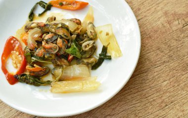  Baharatlı kızarmış midye dilimlenmiş soğan ve tabakta fesleğen yaprağı.