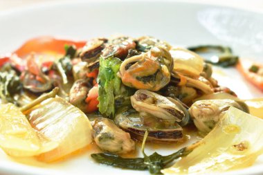  Baharatlı kızarmış midye dilimlenmiş soğan ve tabakta fesleğen yaprağı.
