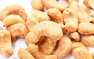  Kızarmış tuzlu kaju fıstığı, beyaz arka planda düzenleniyor.