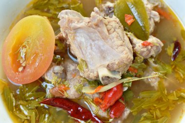  Demirhindi yaprağıyla sıcak ve baharatlı domuz kemiği ve kasede Tayland bitkisi çorbası. 