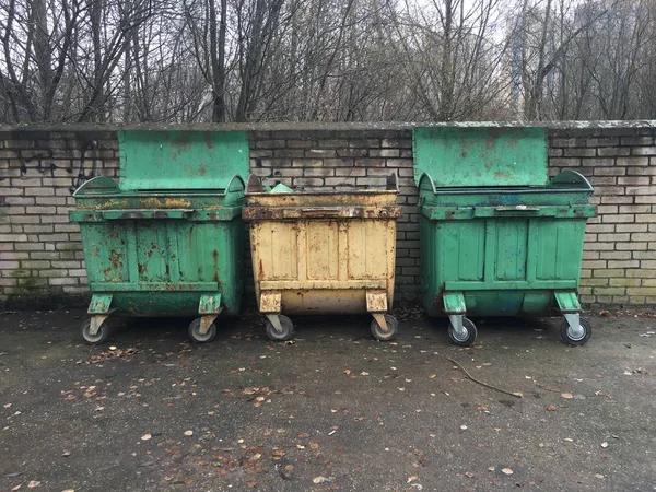 Three garbage cans with wheels and folding lids.