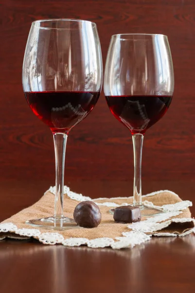Dos copas de vino sobre una mesa de madera. Caramelos . — Foto de Stock