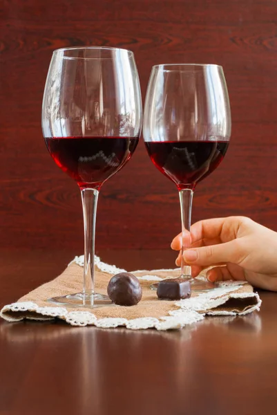 Dos copas de vino sobre una mesa de madera. Caramelos. Manos. . — Foto de Stock