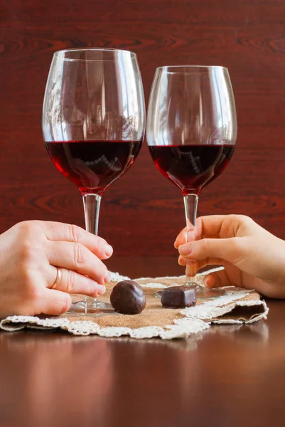 Dos copas de vino sobre una mesa de madera. Caramelos. Manos. . — Foto de Stock