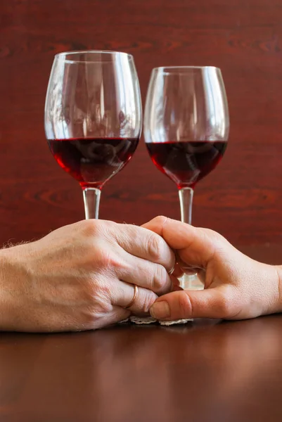 Dos copas de vino sobre una mesa de madera. Manos. . — Foto de Stock