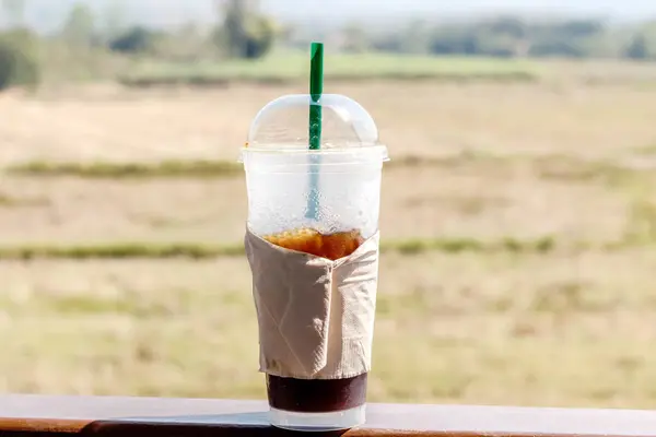 Ледяной кофе с соломой в пластиковой чашке на деревянном столе в сумме — стоковое фото