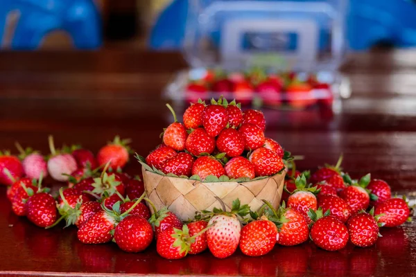 Ripe strawberries with leaves in wicker basket on wooden table o — Stock Photo, Image