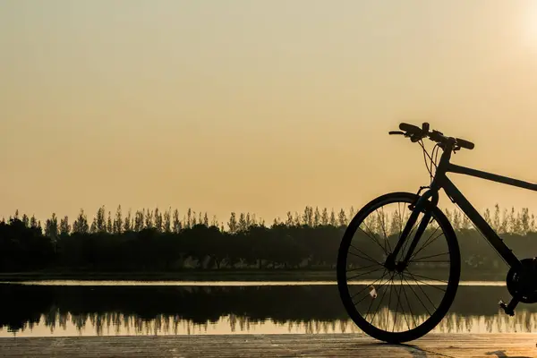 Sylwetka rowerów w pobliżu jeziora i zachód słońca w piękne niebo — Zdjęcie stockowe
