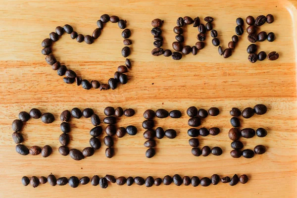 Ziarna kawy są dosłownie "Uwielbiam kawę" na drewnianą podłogę. — Zdjęcie stockowe