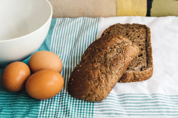 Färska ägg och brunt bröd på duken — Stockfoto