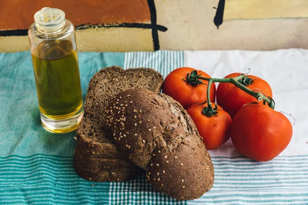 Olivolja, tomat och brunt bröd på duken — Stockfoto