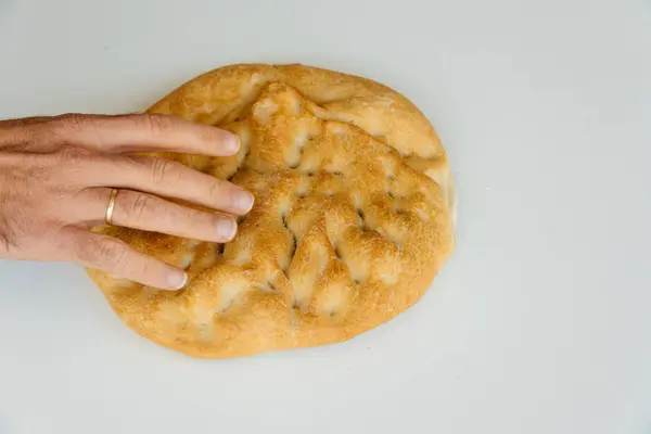 Mannen hand på limpa bröd på vitt bord, mat närbild. Ovanifrån — Stockfoto