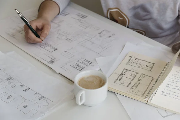 Mladé samice architekt pracuje na náčrtky s šálkem kávy — Stock fotografie
