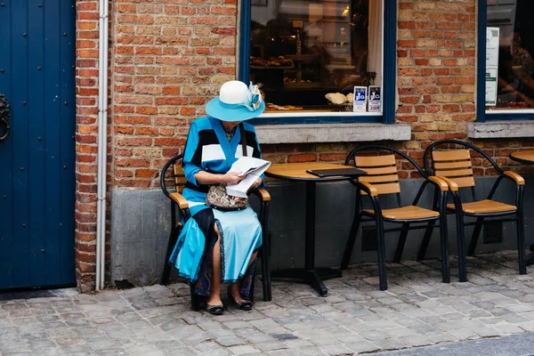 Régi kifinomult nő öltözve kék ül a teraszon az utcán a Bruges. — Stock Fotó