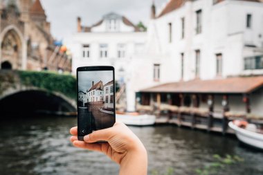 Bruges cityscape fotoğrafta bir telefon tutan kadın