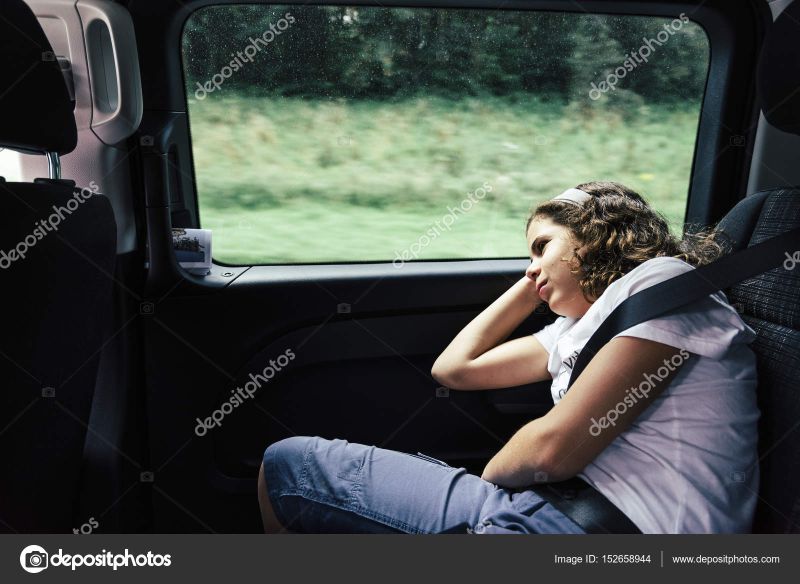 Teenager sleeping in the backseat of a car on a trip Stock Photo by