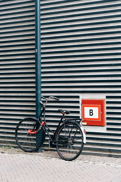 Uma bicicleta velha está em frente à fachada de um arquita moderno — Fotografia de Stock