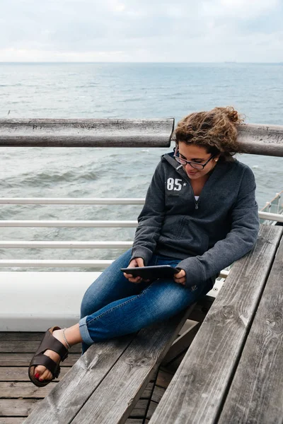 タブレット上の桟橋に座って関連付けられている若い女性、 — ストック写真