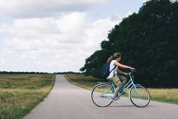 Lächelnde hübsche junge Frau mit Fahrrad auf einer Landstraße in der — Stockfoto