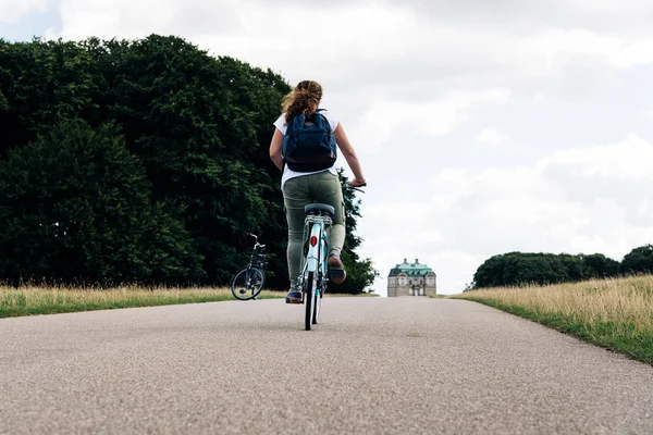 Hübsche junge Frau radelt auf einer Landstraße im Park — Stockfoto