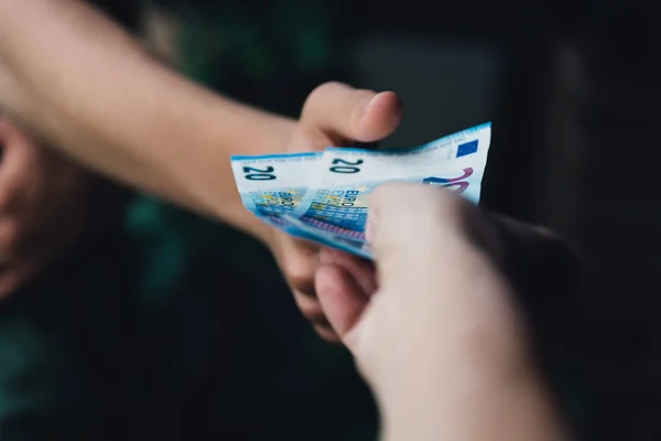 Το χέρι της γυναίκας δίνοντας χρήματα ευρώ σε έναν νεαρό άνδρα — Φωτογραφία Αρχείου