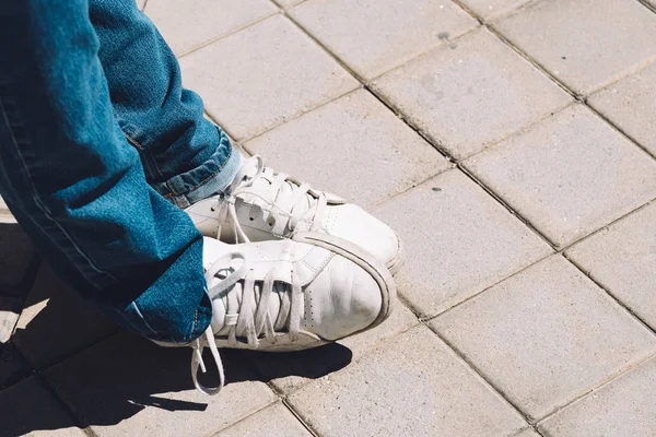 Womens feet in sneakers are standing on the sidewalk — Stock Photo, Image